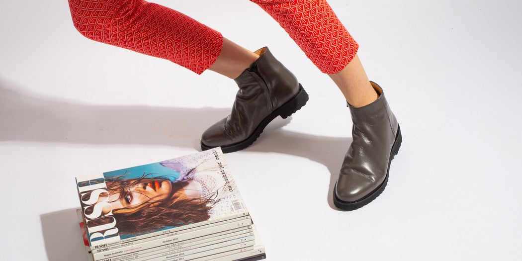Grey Italian leather zip up ankle boot on model with magazine pile