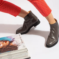 Grey Italian leather zip up ankle boot on model with magazine pile